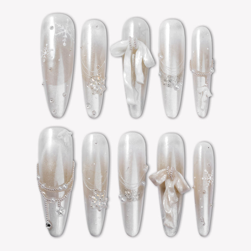 Flat lay of Frosted Ballet press-on nail swatches with pearl white and silver shimmer finishes, snowflake accents, and ribbon bows