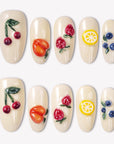 Fruit Crush cream press-on nails with glossy 3D cherries, peach, strawberries, lemon, and blueberries in a white flat lay