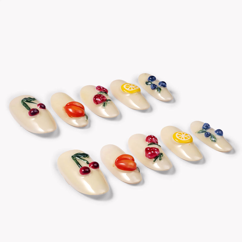Angled flat lay of Fruit Crush glossy cream press-on nails with colorful raised cherry, peach, berry, and lemon designs