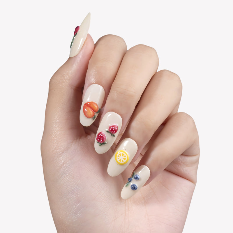 Fruit Crush cream almond press-on nails with raised peach, strawberry, lemon, cherry, and blueberry art on a hand model