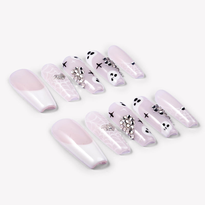 Angled flat lay of Ghosted Love press-on nails with pink translucent bases, white spider webs, ghost faces, silver rhinestones, and heart accents