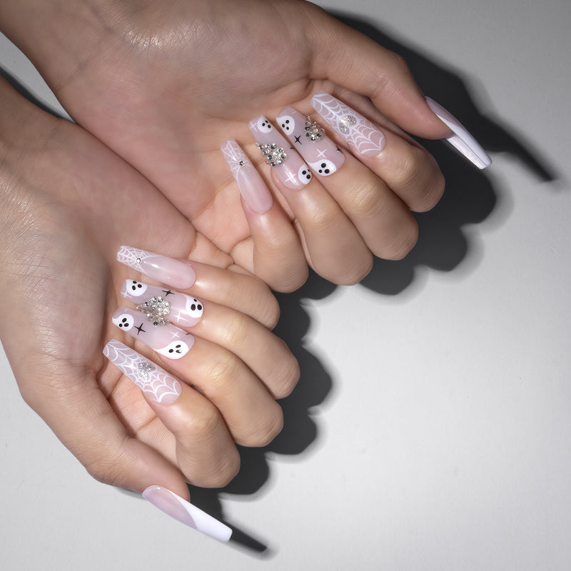 Two-hand model wearing Ghosted Love press-on nails with pink bases, white spider webs, ghost faces, silver rhinestones, and star accents