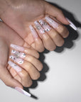 Two-hand model wearing Ghosted Love press-on nails with pink bases, white spider webs, ghost faces, silver rhinestones, and star accents