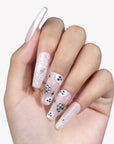 White background hand model wearing Ghosted Love press-on nails with pale pink bases, white spider webs, ghost faces, and silver rhinestone details