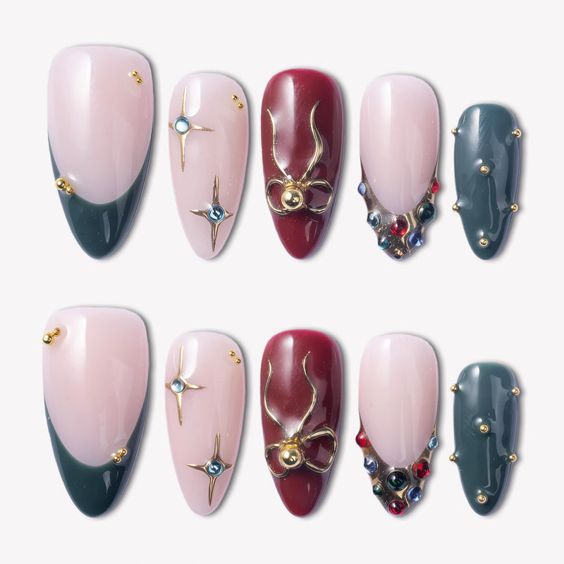 Gilded Noel press-on nails in burgundy, deep teal, and nude pink with gold bows, starbursts, pearls, and jewel accents