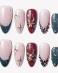 Gilded Noel press-on nails in burgundy, deep teal, and nude pink with gold bows, starbursts, pearls, and jewel accents