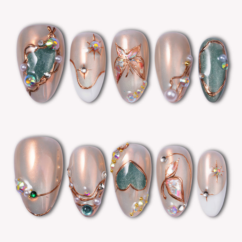 A set of champagne shimmer press-on nails with olive green accents, butterfly details, pearls, and rhinestones on a white background