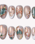 A set of champagne shimmer press-on nails with olive green accents, butterfly details, pearls, and rhinestones on a white background