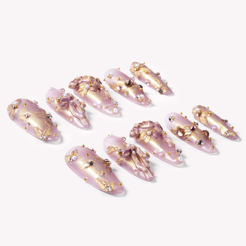 Flat lay of Gilded Petal Waltz press-on nails in soft lavender and gold with floral accents, pearls, and rhinestones