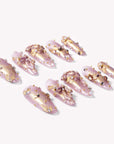 Flat lay of Gilded Petal Waltz press-on nails in soft lavender and gold with floral accents, pearls, and rhinestones