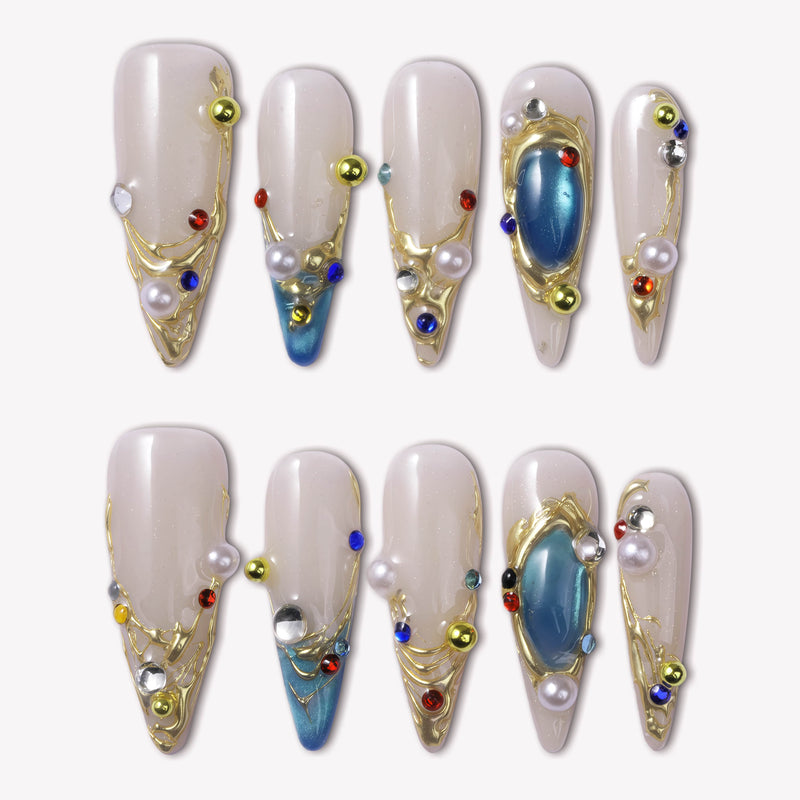 Gilded Relic Blue almond press-on nails with gold sculpted accents, pearls and colorful rhinestones in a flat lay