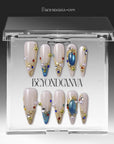 Gilded Relic Blue press-on nails displayed in clear packaging with blue gems, pearls, and gold accents