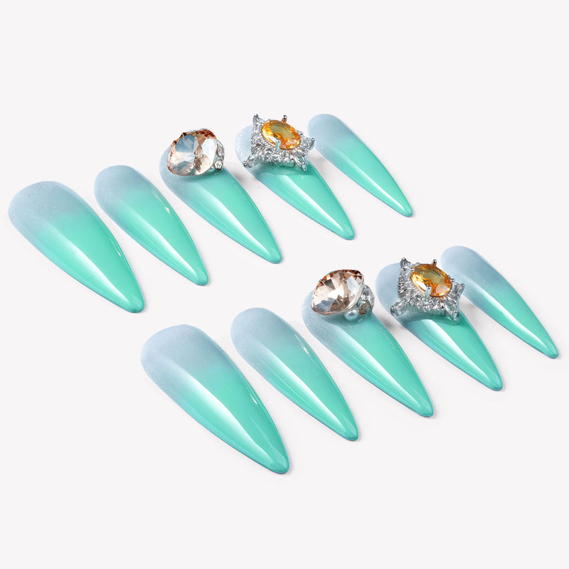 Flat lay of Glacier Jewel press-on nails arranged in two rows with icy blue ombré and yellow crystal embellishments