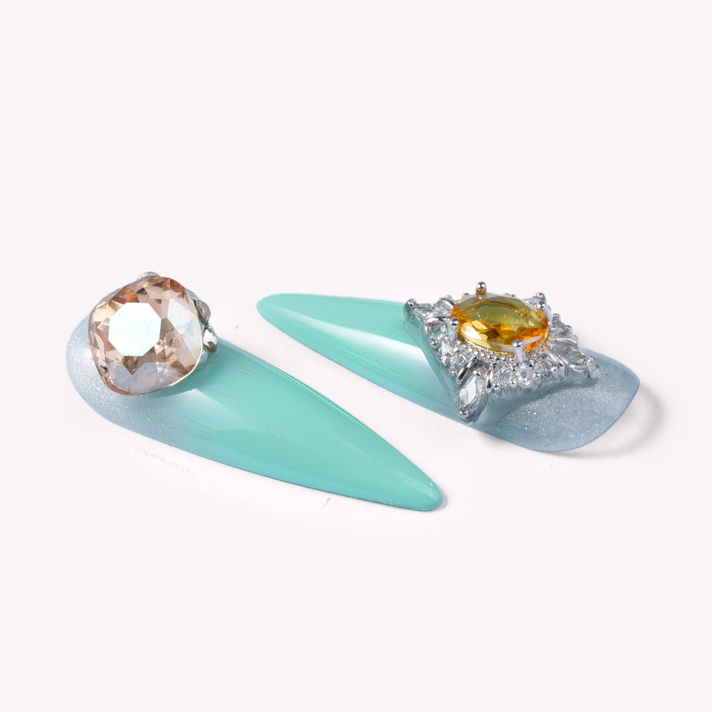 Closeup of Glacier Jewel press-on nails with mint blue ombré and oversized yellow and clear gemstone accents