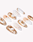 Angled flat lay of Golden Shell white and gold seashell nails with pearls and sculpted shell details