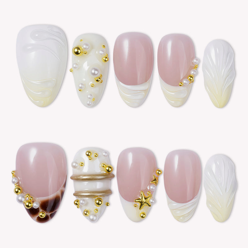Hand model wearing Golden Shore Ritual handmade press-on nails with pearl white, blush pink, and gold accents.