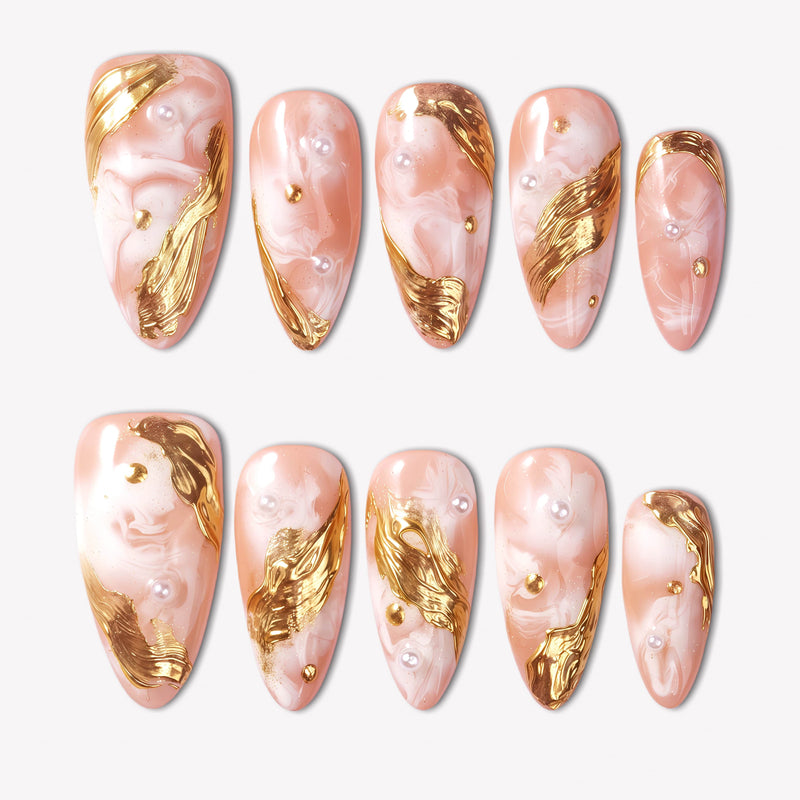 Golden Veil peach marble press-on nails with sculpted gold foil accents and pearl embellishments in a flat lay
