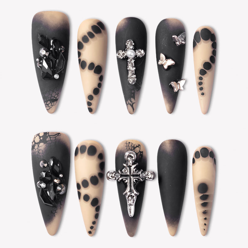 Gothic Elegance press-on nails with matte black and nude designs, silver cross charms, black rhinestones, lace effects, and butterfly accents