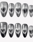 Gravity black and silver cat-eye glitter press-on nails with a glossy finish arranged in a white flat lay