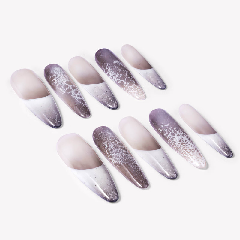 Angled flat lay of Himalayan Mist press-on nails with gray lilac mist gradient, white French tips, silver crackle lines, and lace-like texture