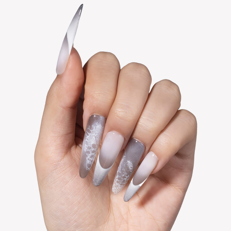 Hand model wearing Himalayan Mist press-on nails with gray lilac mist gradient, white French tips, silver crackle lines, and lace-like texture