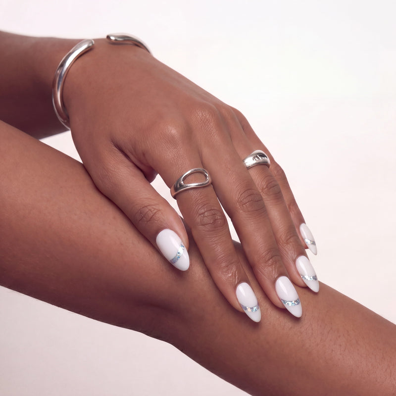 Hand model wearing white press-on nails with iridescent chrome shimmer accents.