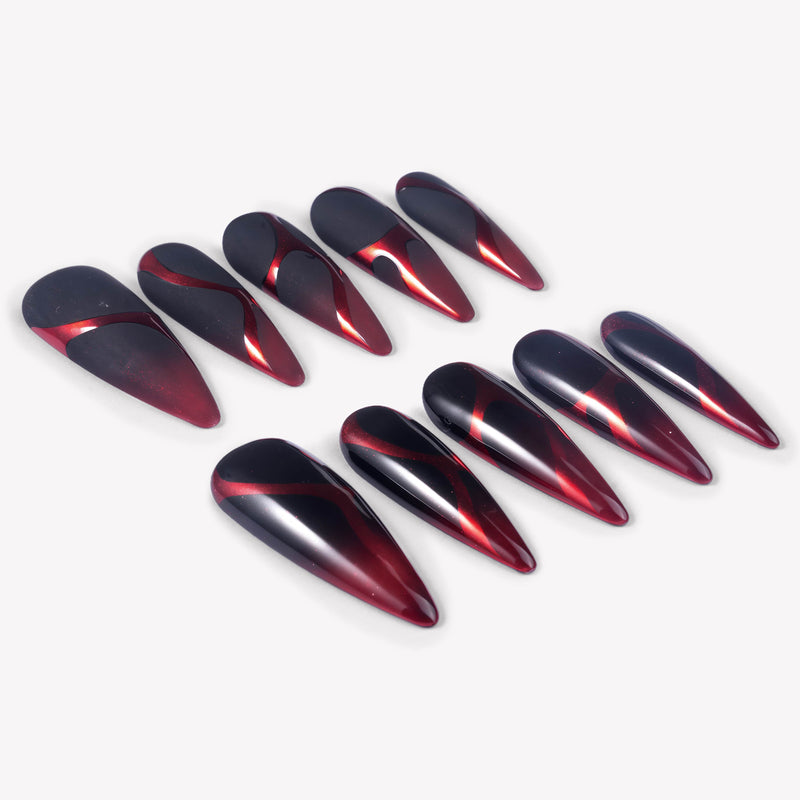 Angled flat lay of Inferno Veins stiletto press-on nails with metallic red gradients, matte black panels, glossy black sections, and vein-like curves