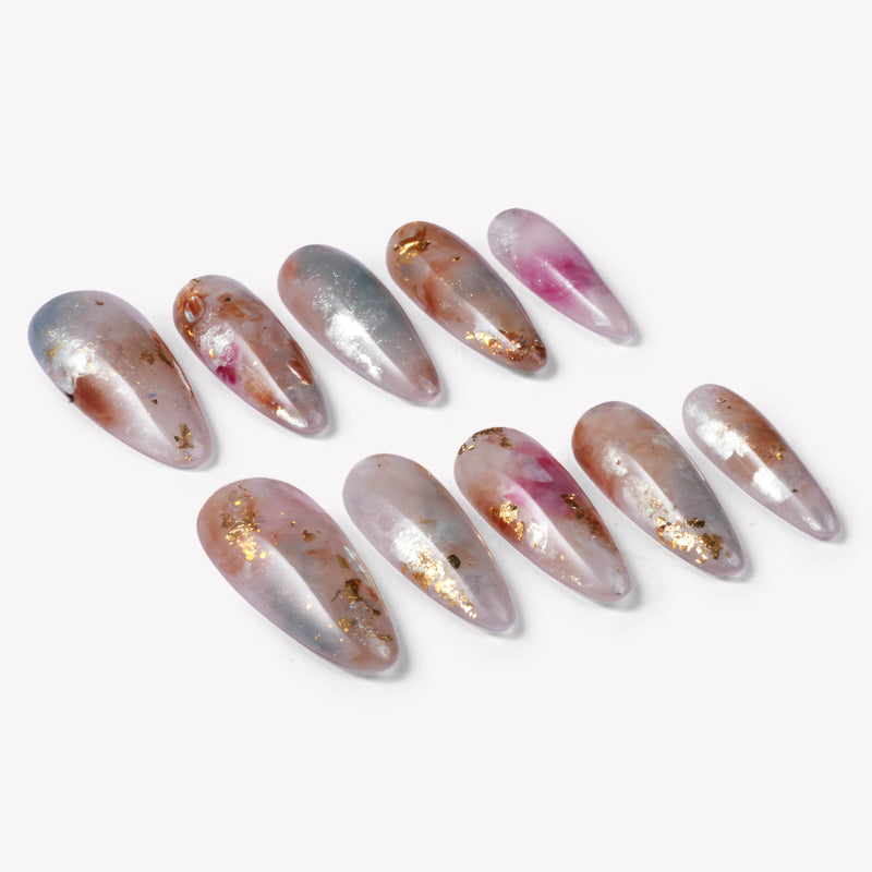 Flat lay of iridescent pearl press-on nail swatches in silver, blush pink, and gold foil