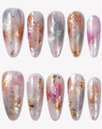 Flat lay of iridescent pearl press-on nails in silver, blush pink, and gold foil on a white background