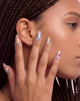 Profile portrait of a hand model wearing iridescent pearl press-on nails in silver, blush pink, and gold foil