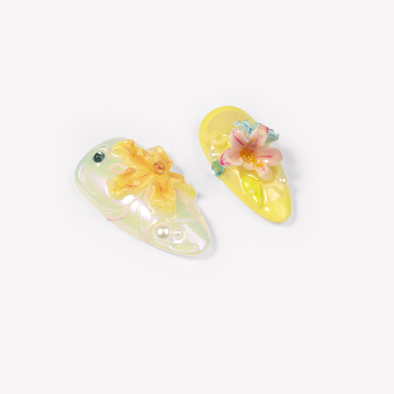 Close-up of two Iridescent Petals yellow press-on nails with raised pink and yellow flowers, pearls and gems