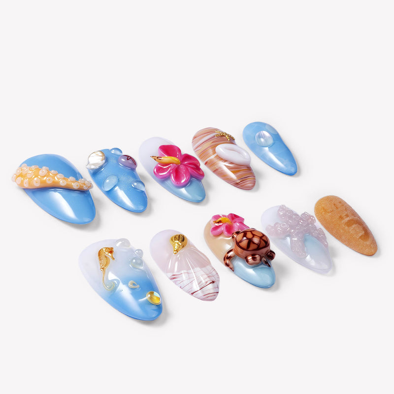 Angled flat lay of Island Echo blue and coral tropical press-on nails with flower, shell, turtle and sea details