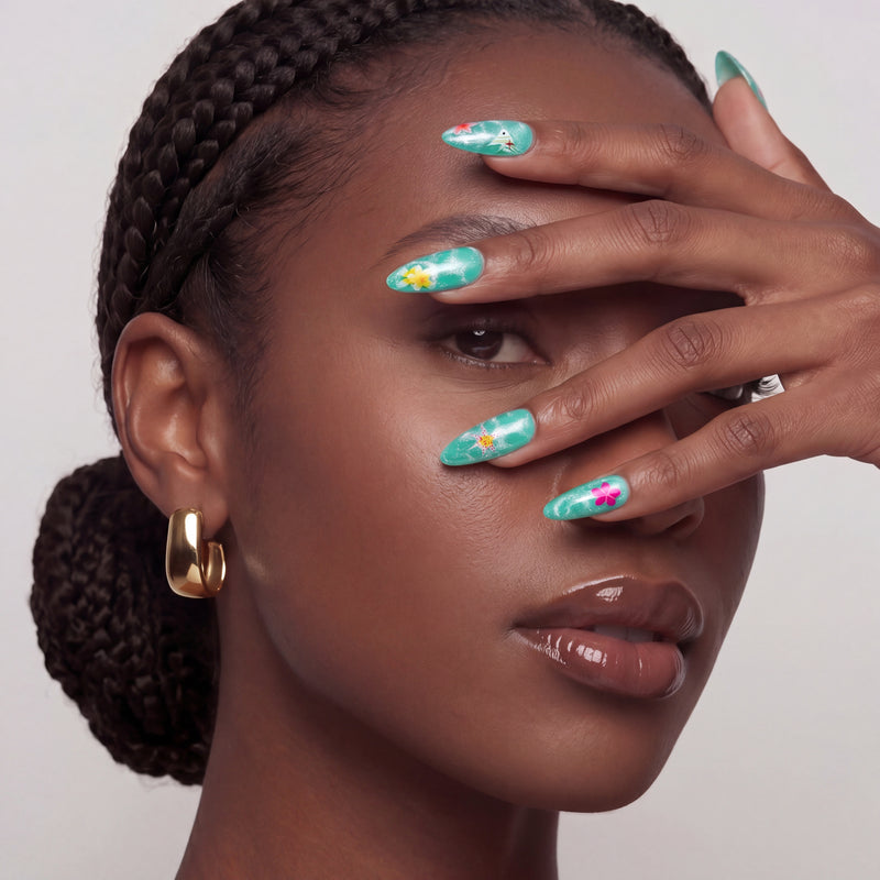 Hand model wearing turquoise almond press-on nails with yellow and pink floral accents