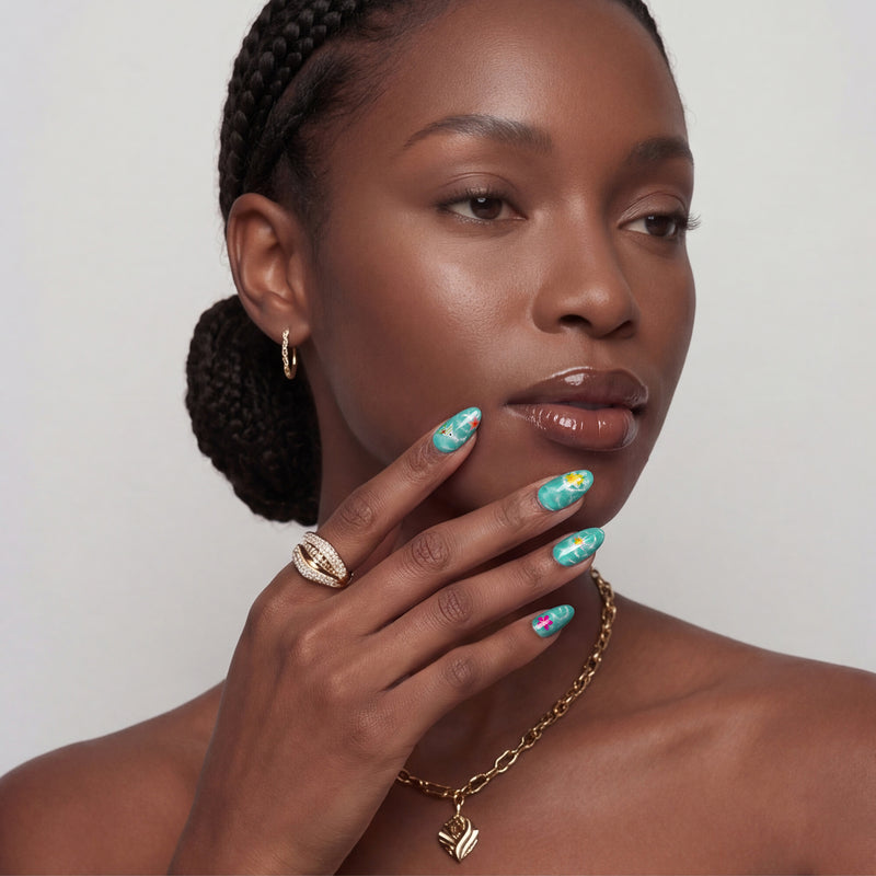 Portrait of a hand model wearing turquoise almond press-on nails with yellow and pink floral accents