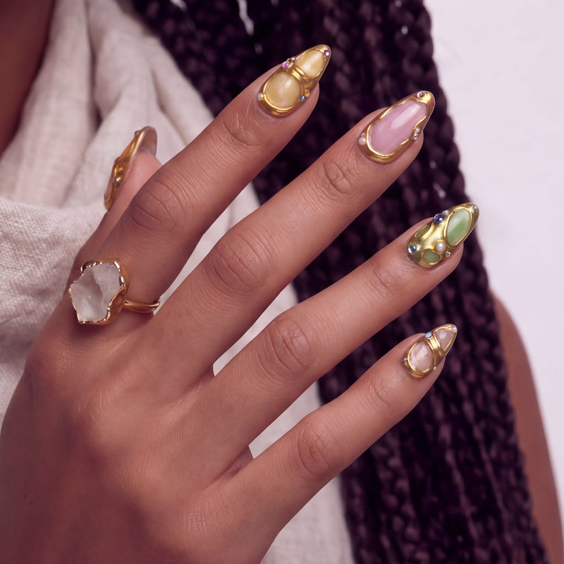 Close-up hand model with a crystal ring wearing Jewel Mosaic pastel press-on nails with raised gold frames and gems