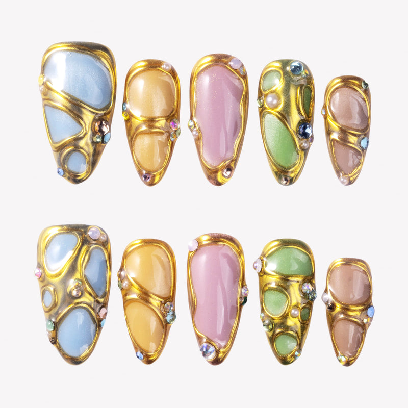 Jewel Mosaic press-on nails with pastel stained-glass panels, raised gold outlines, pearls, and colorful rhinestones