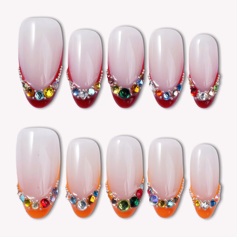 Flat lay of Jewel Sunset press-on nail swatches with soft pink bases, ruby red tips, and multicolor gem accents