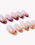 Flat lay of Jewel Sunset press-on nail swatches with ruby red and orange tips and multicolor gem accents