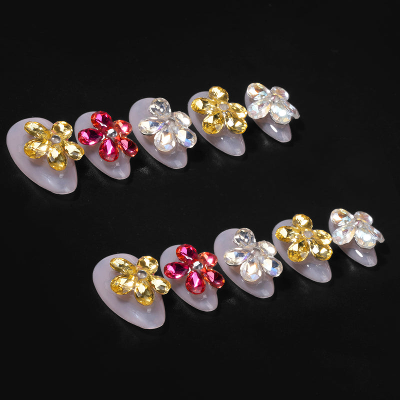 Two rows of jeweled floral press-on nail tips arranged on a black background.