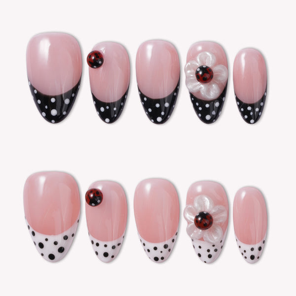 Ladybug Garden press-on nails with pink bases, black and white polka dot French tips, red ladybugs, and white flower charms