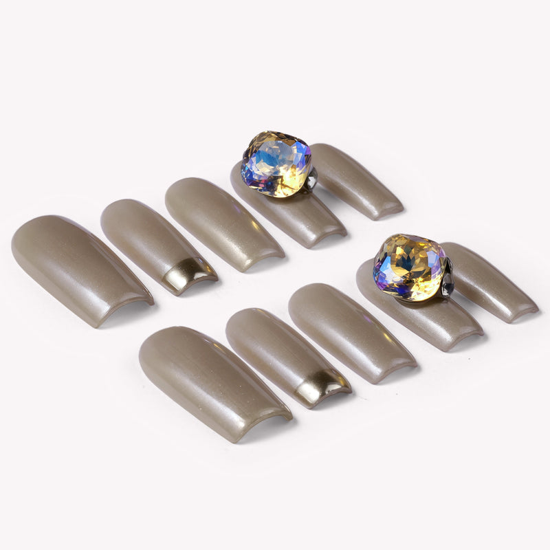 Flat lay of champagne metallic press-on nails with two iridescent gemstone accents