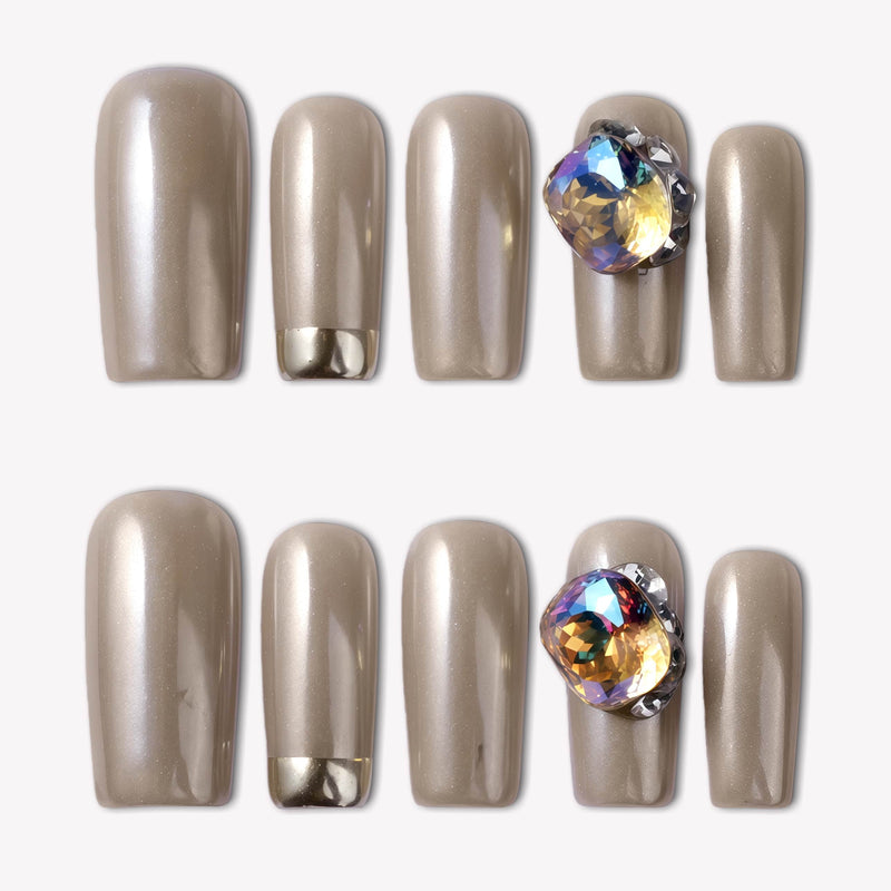 Flat lay of champagne metallic press-on nails with an iridescent gemstone accent