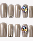 Flat lay of champagne metallic press-on nails with an iridescent gemstone accent