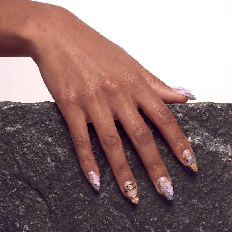 Lavender Lyric handmade press on nails worn on a hand model with a dark stone background and lavender floral accents