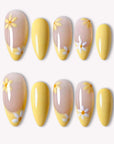 Lemon Bloom yellow press-on nails with nude bases, white daisy flowers and glossy yellow tips