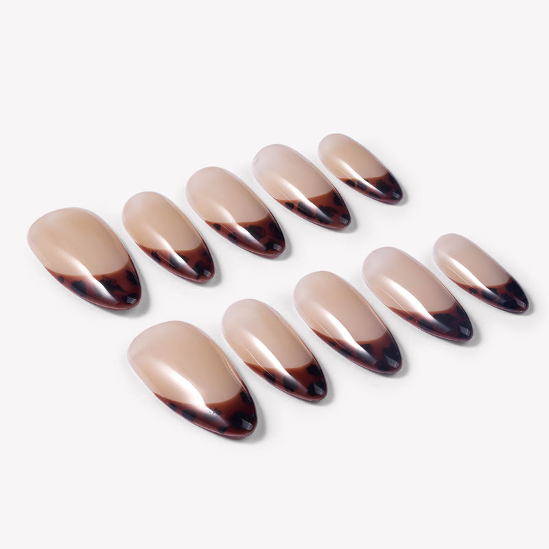 Angled flat lay of Leopard French press-on nails with glossy nude bases and deep brown black animal print French tips
