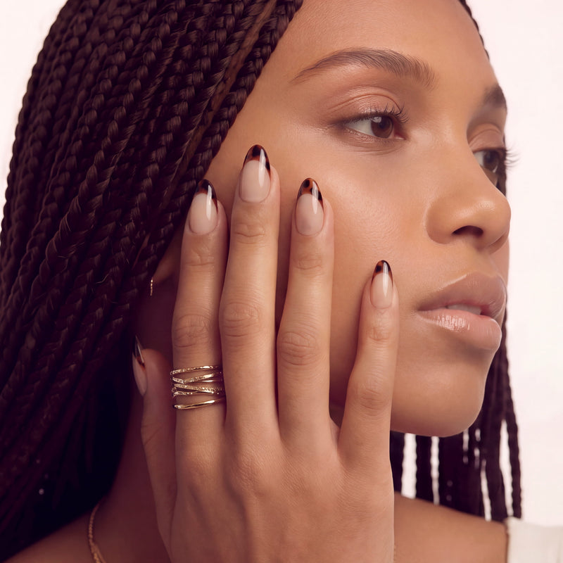 Portrait close-up of a hand model wearing Leopard French press-on nails with nude bases and brown black animal print French tips