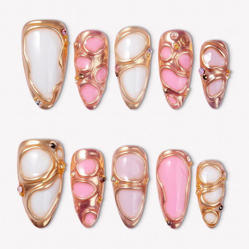 Liquid Gold pink and white press-on nails with raised rose gold frames and crystal accents in a flat lay
