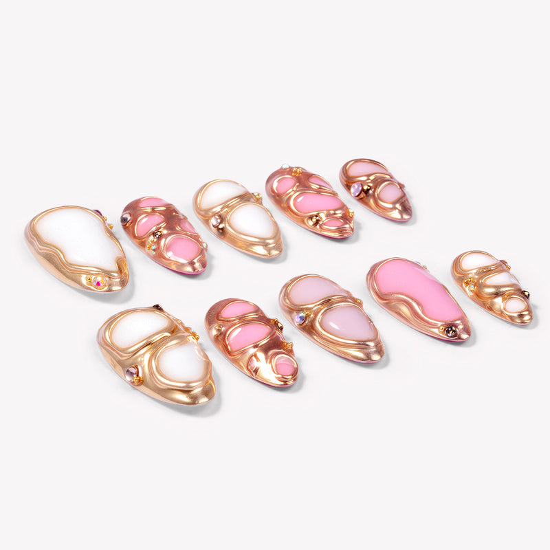 Angled flat lay of Liquid Gold pink and white press-on nails with raised rose gold frames and crystal accents