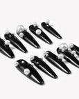 Diagonal flat lay of Louboutin Pearl Noir press-on nails with glossy black finish and pearl embellishments